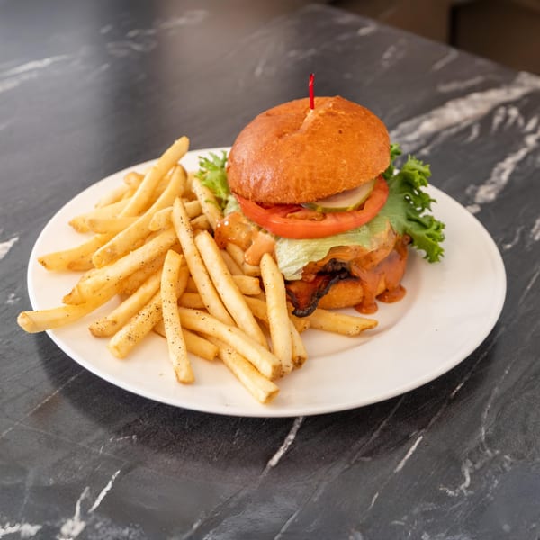 Bell the Cat's burger with lettuce, tomato, pickles, and sauce, served with fries.